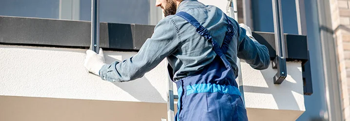 Person auf Leiter montiert Geländer an Balkon